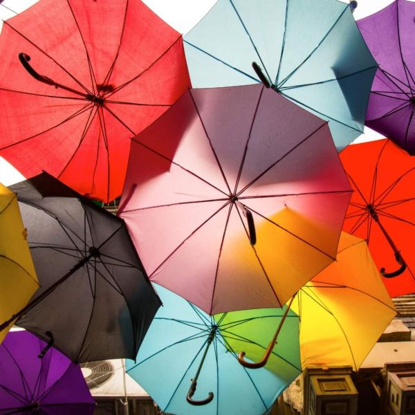 Viele bunte Regenschirme scheinen zu schweben, fotografiert von unten.